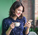 Woman in cafe smiling while looking at phone