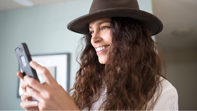 Young woman with hat looking at phone inside