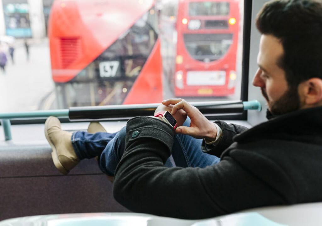 UK, London, young man in a double-decker bus using his smartwatch